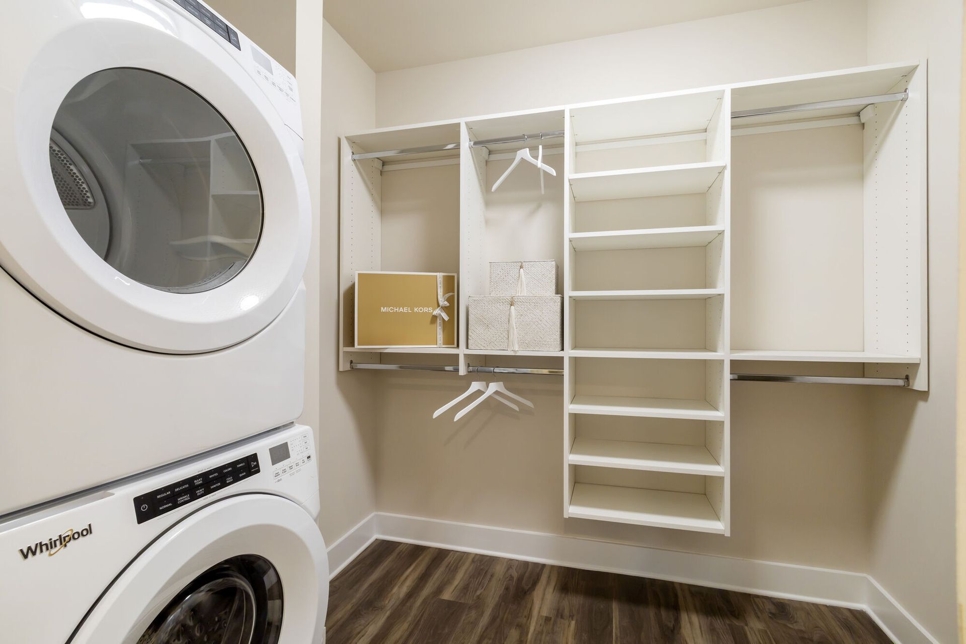 In-unit laundry closet with a stacked washer and dryer and white shelving.