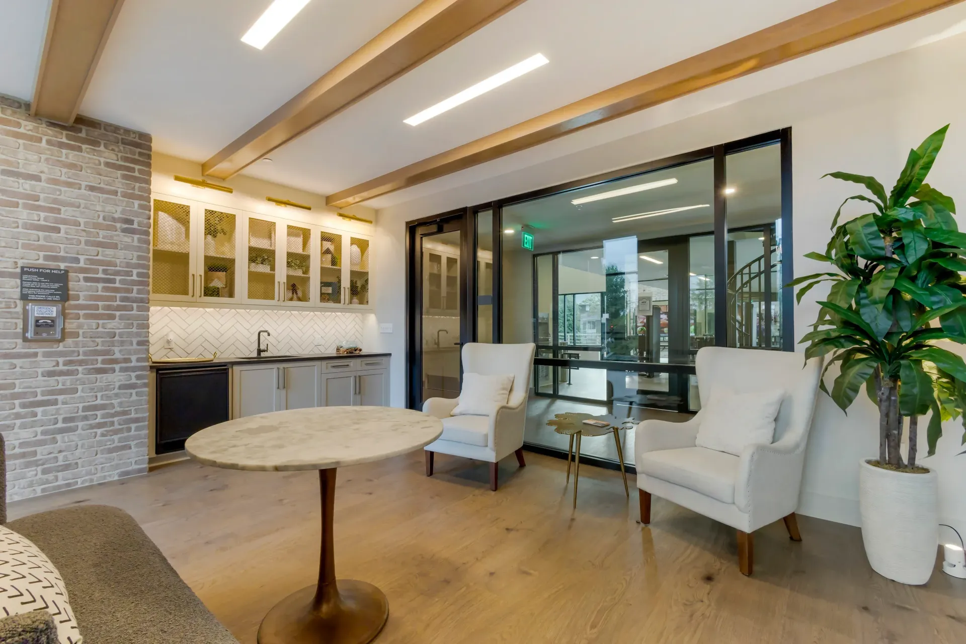 Indoor resident lounge with kitchenette, seating area, and large glass doors.