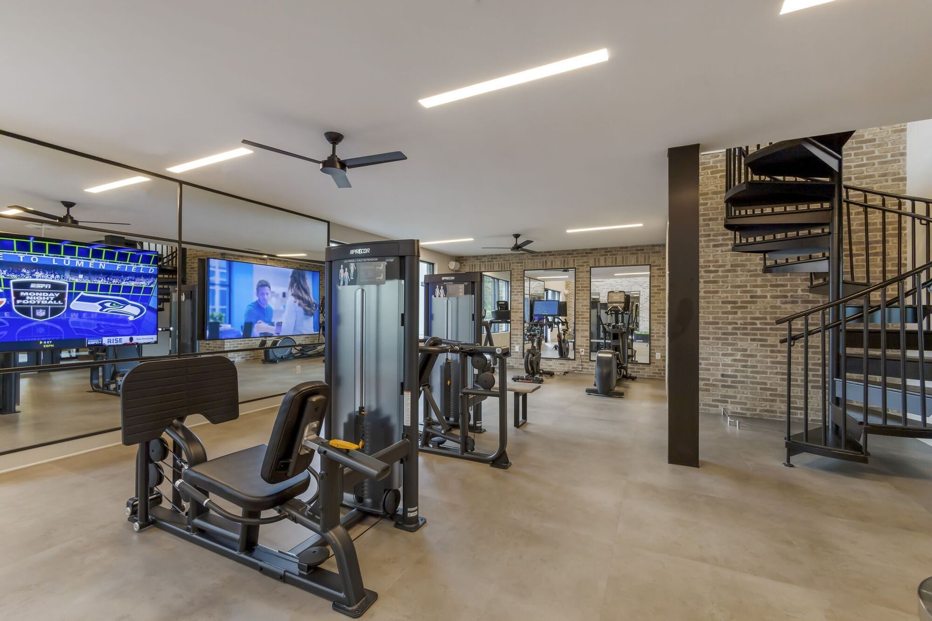 Modern fitness center with cardio and strength equipment, mirrors, and brick-walled interior.