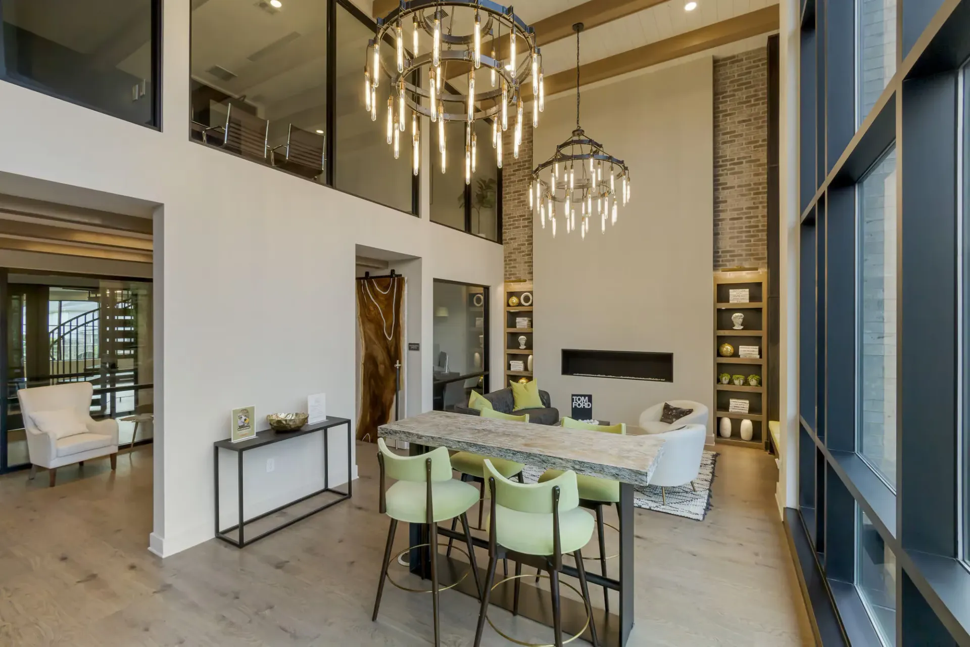Modern lobby with two circular chandeliers, seating area, and floor-to-ceiling windows.