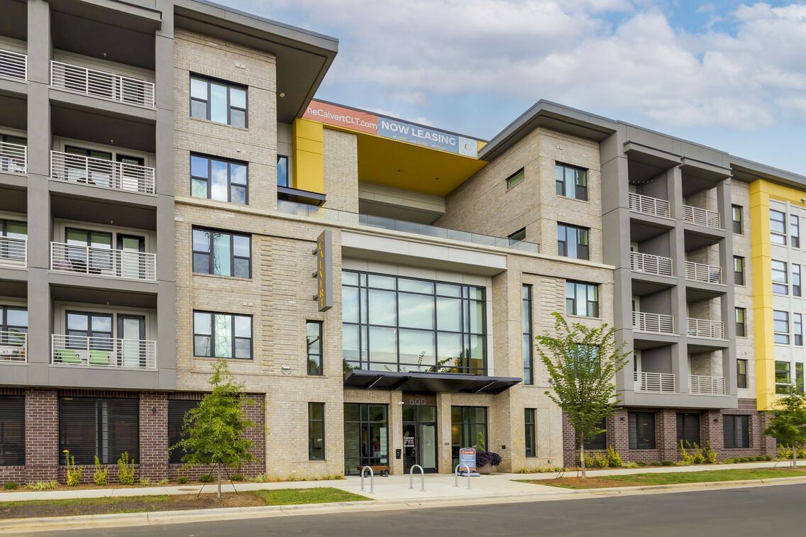 Exterior view of a modern apartment building with balconies and a glass entrance.