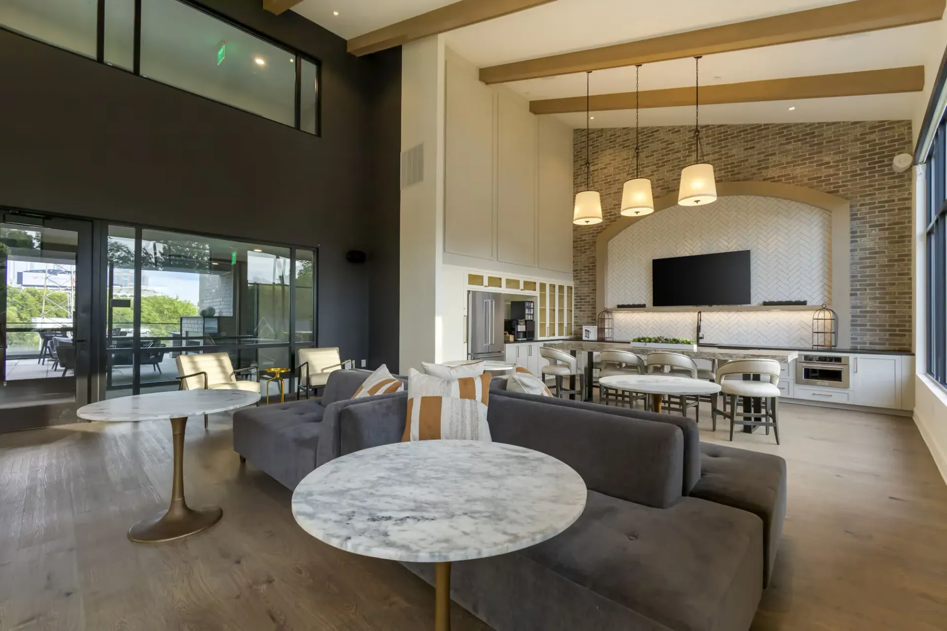 Modern apartment community lounge with seating, marble tables, and a large TV.
