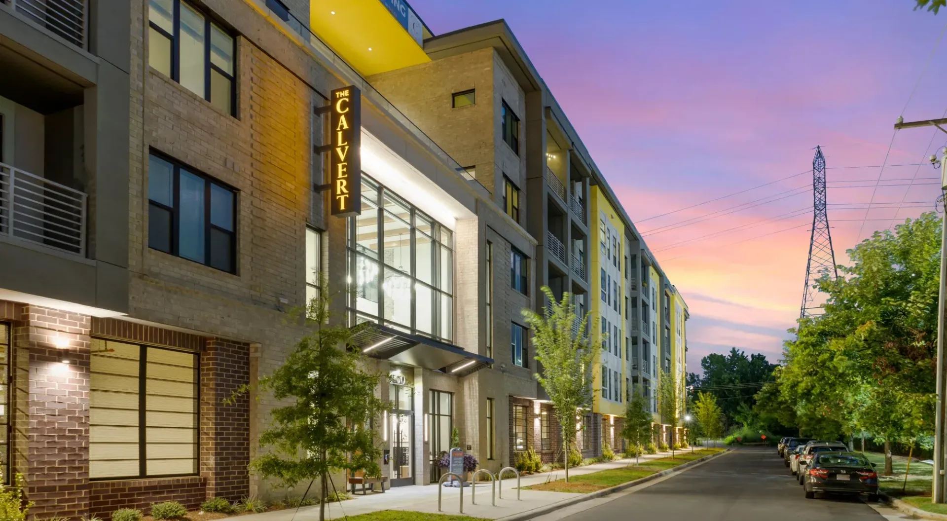 Exterior view of a modern apartment building at dusk with a lit 'The Calvert' sign.
