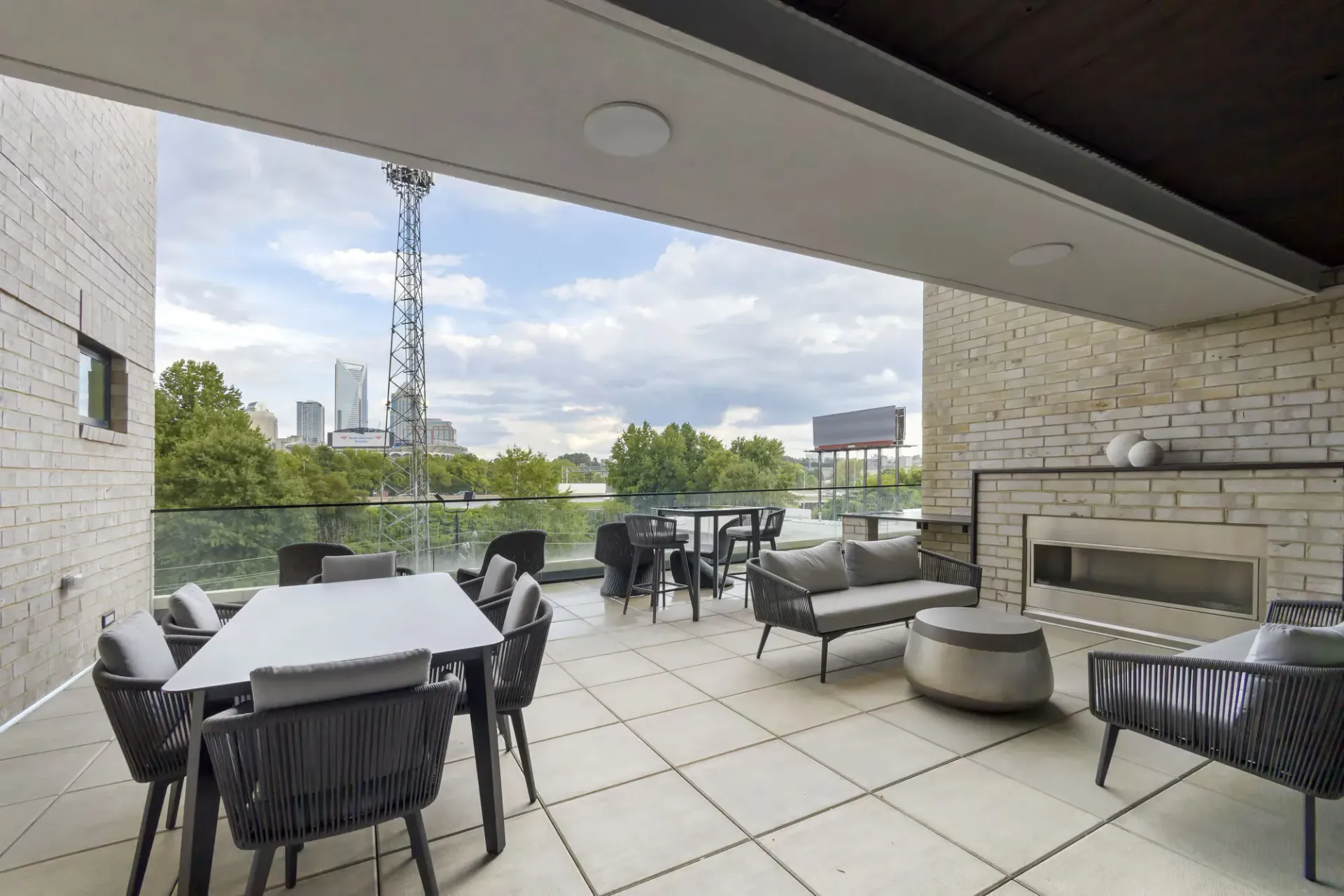 Rooftop lounge with modern seating and a fireplace, overlooking the city skyline.
