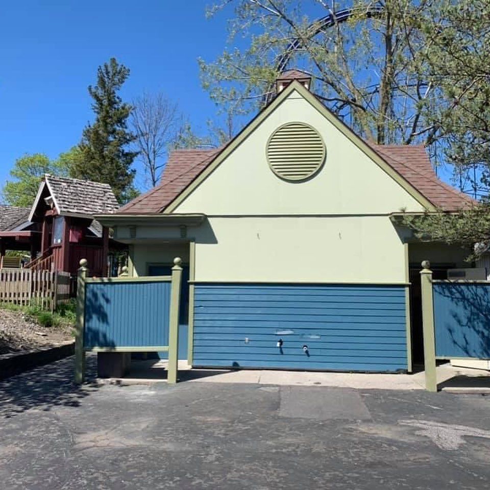 A green house with a blue garage door