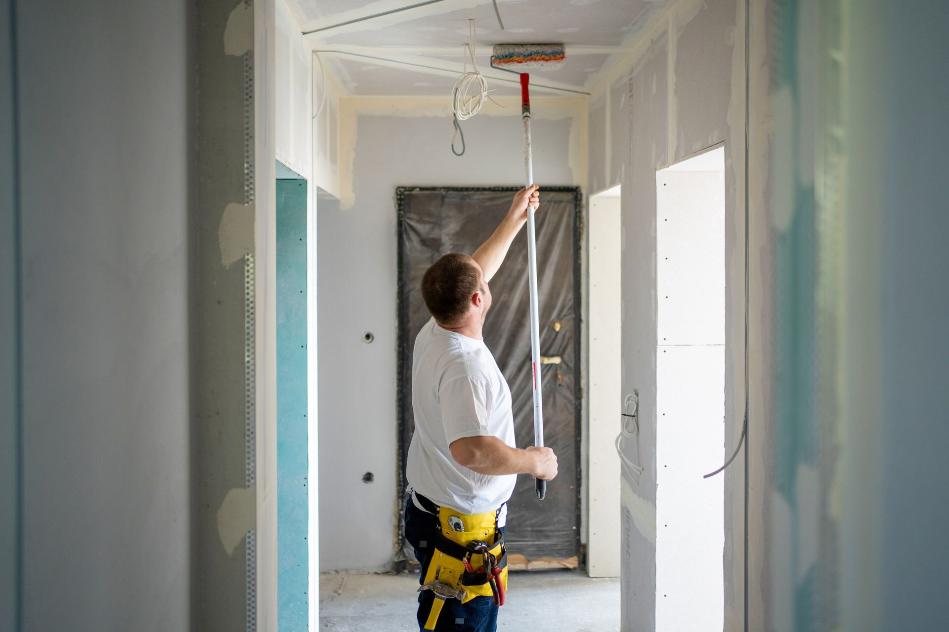 A man is painting the ceiling of an apartment.