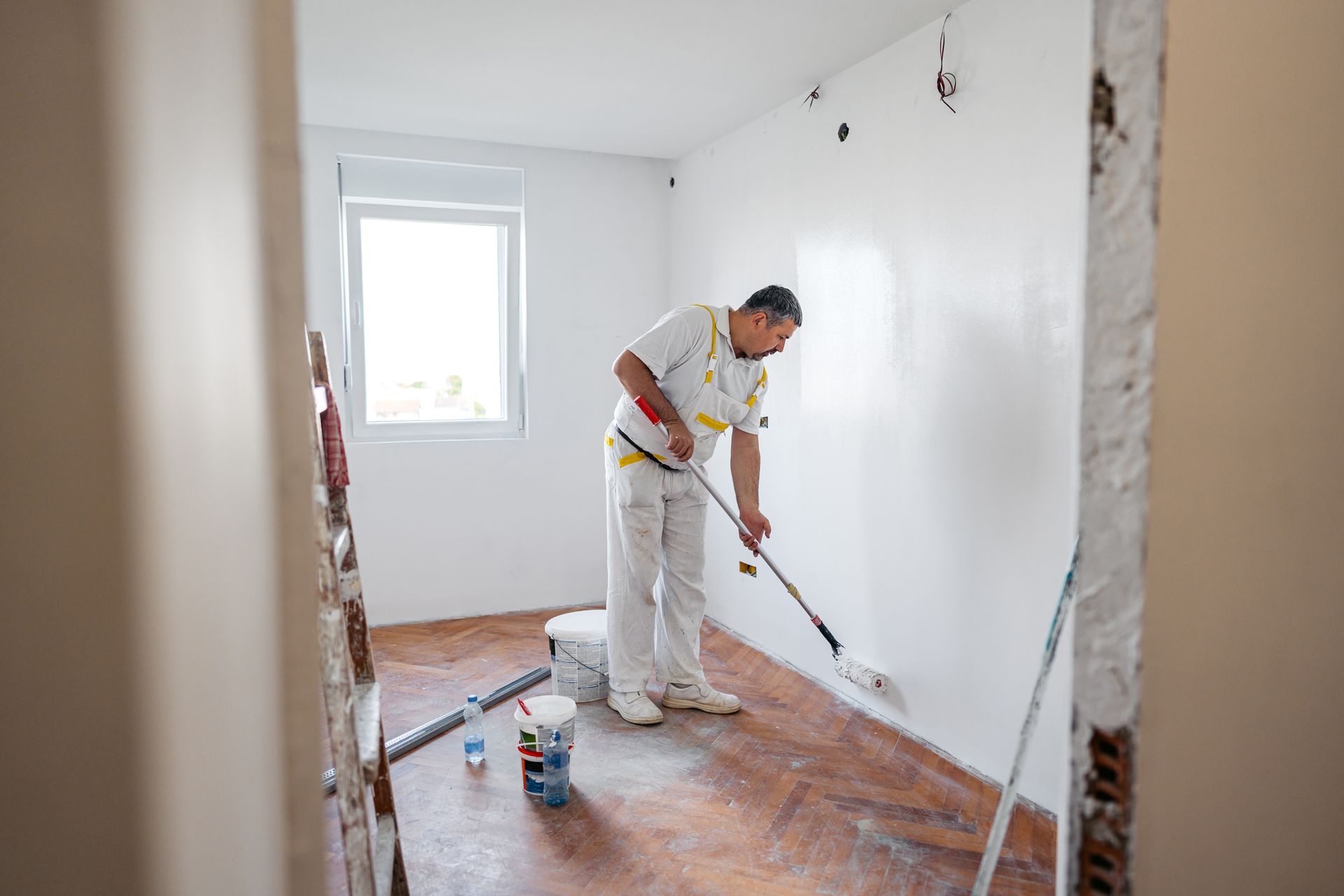 A worker is painting the walls with a paint roller.