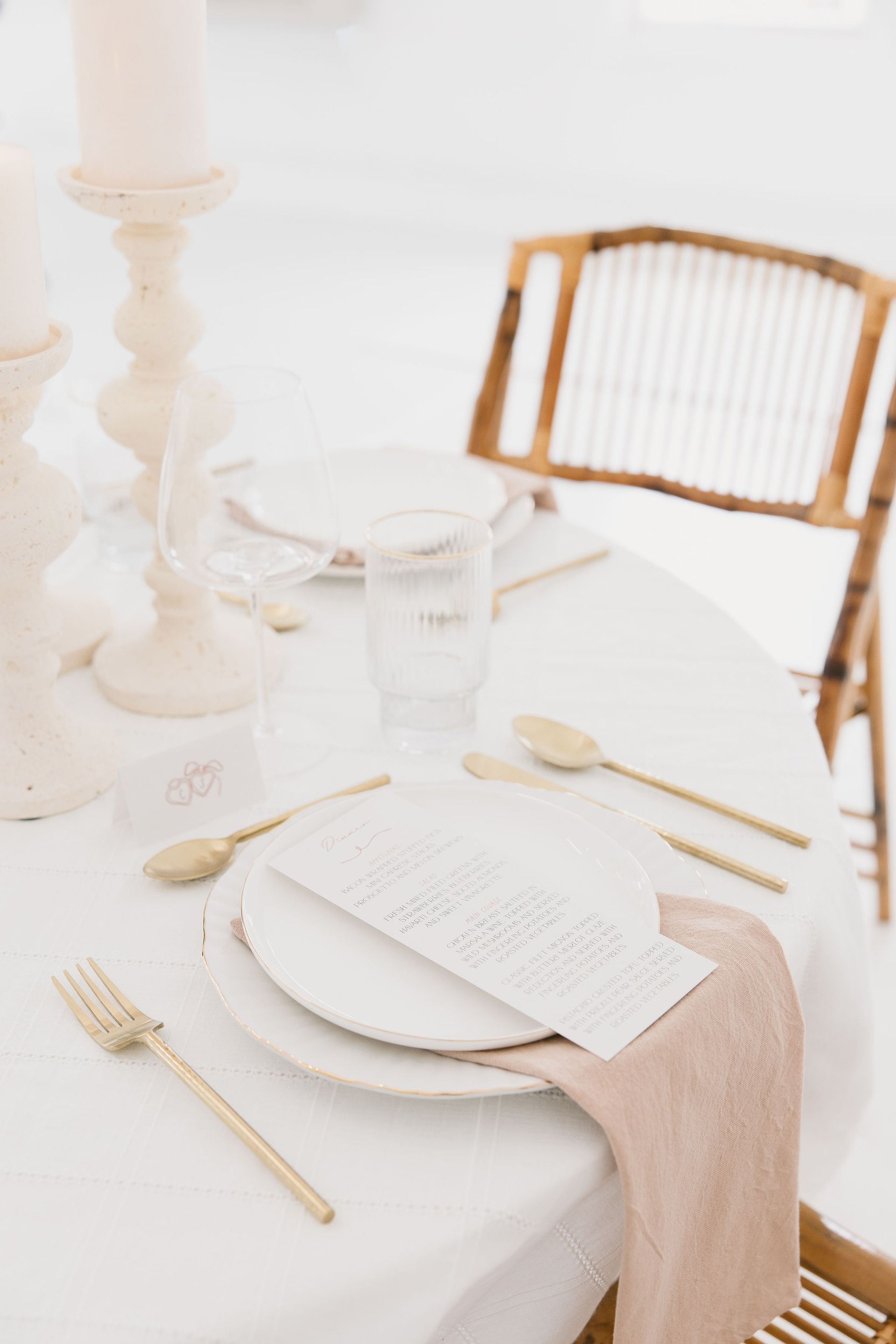 A table set for a wedding reception with plates , silverware , and candles.