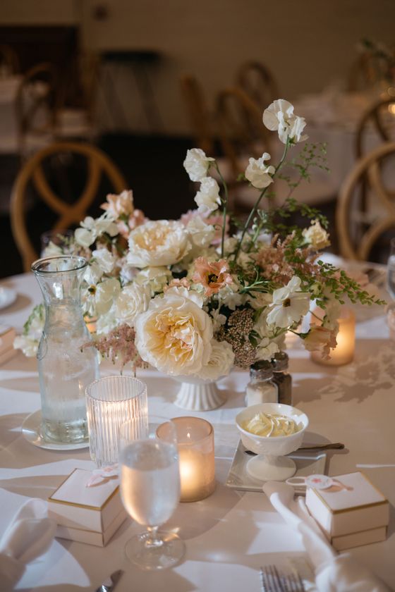 A table with a vase of flowers and candles on it at a Luxury wedding.