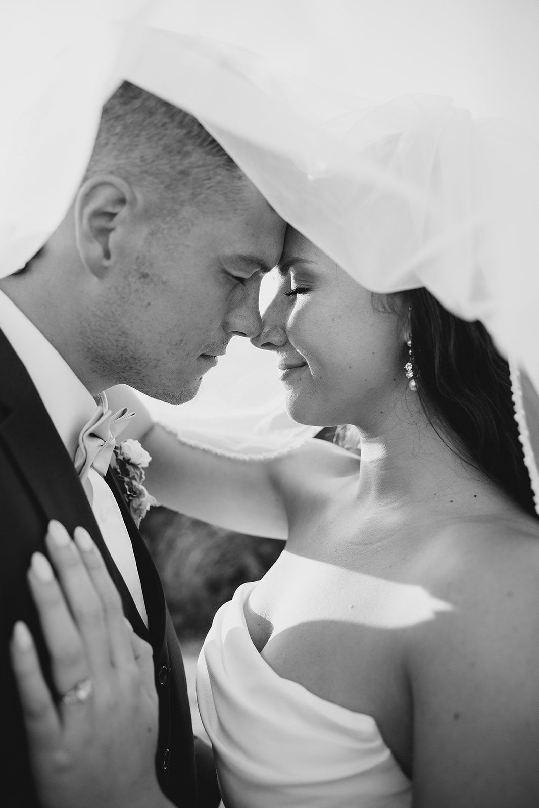 A black and white photo of a bride and groom looking into each other 's eyes.