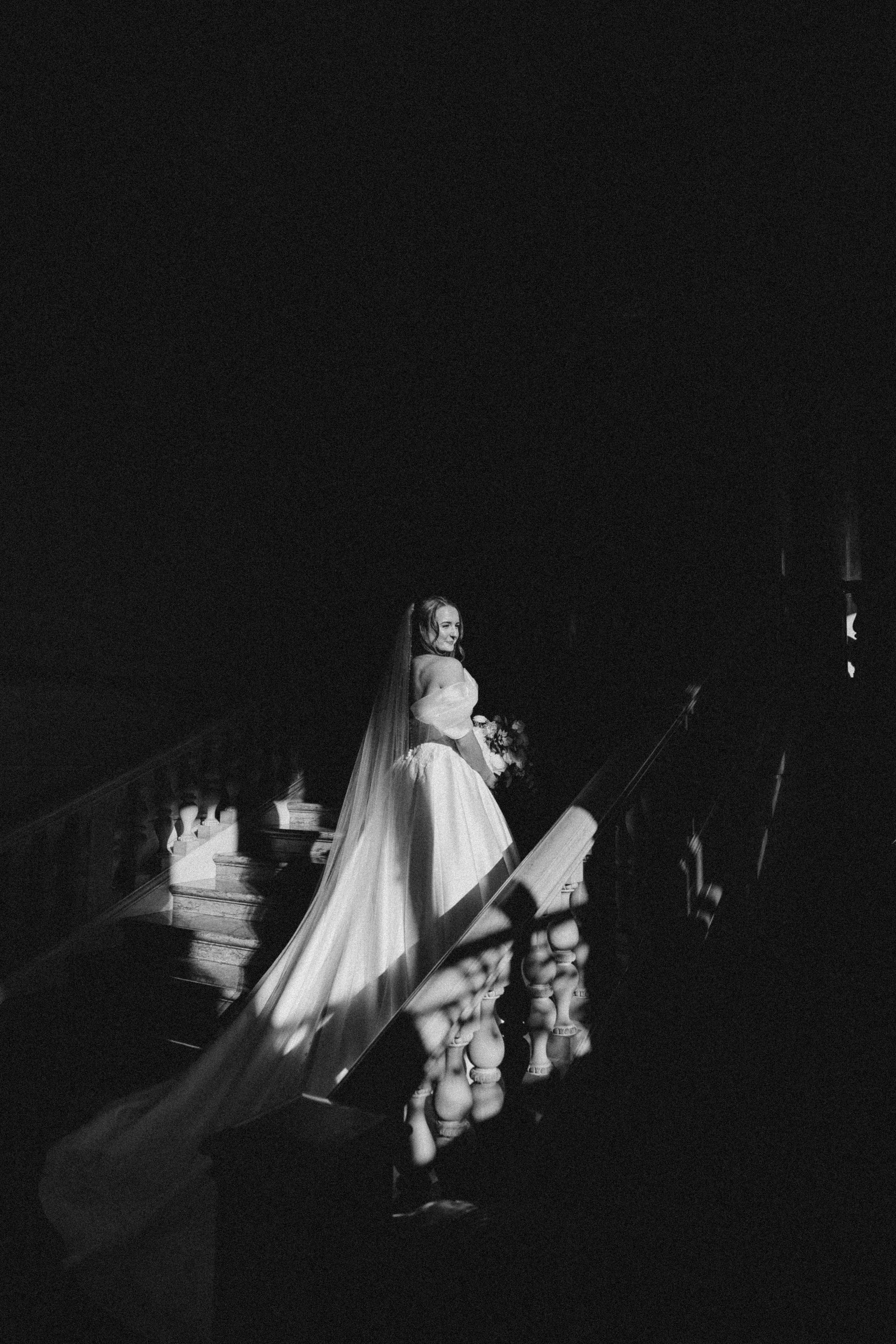 A black and white photo of a bride and groom standing on a balcony at night in Newport RI