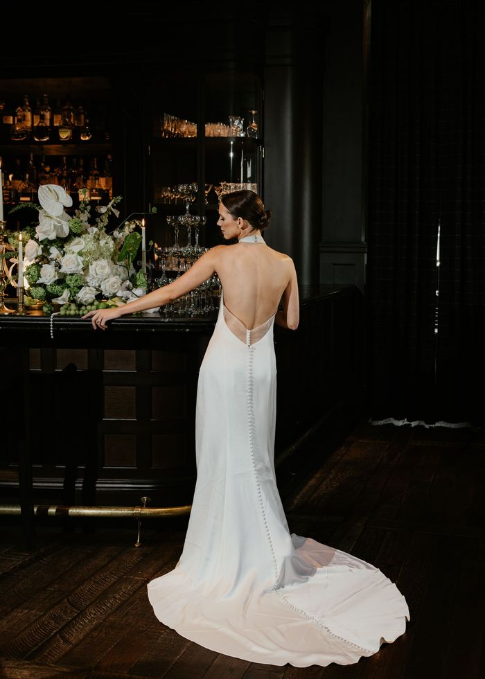 A woman in a wedding dress is standing in front of a bar at a luxury hotel in Newport, RI.