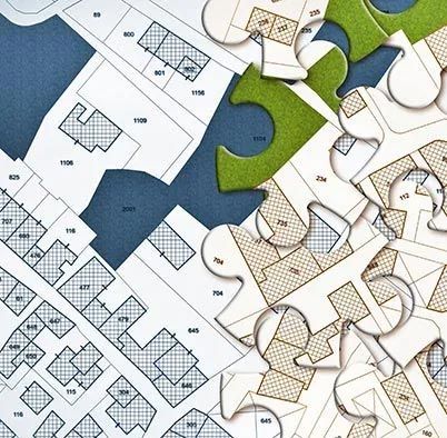 Close-up of interlocking jigsaw puzzle pieces with blue, green, and tan sections over a floor plan.