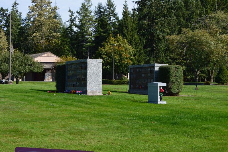 Memorial stones and plaques on a green lawn with trees in the background