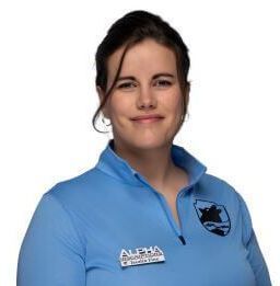 A woman in a blue shirt is smiling for the camera.