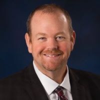 A man in a suit and tie is smiling for the camera.