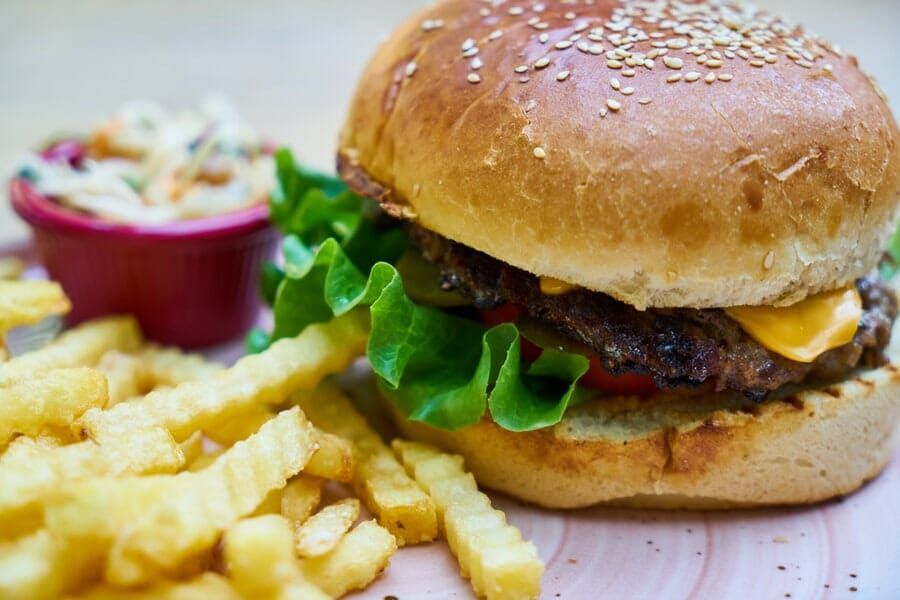 A hamburger and french fries are on a wooden table.