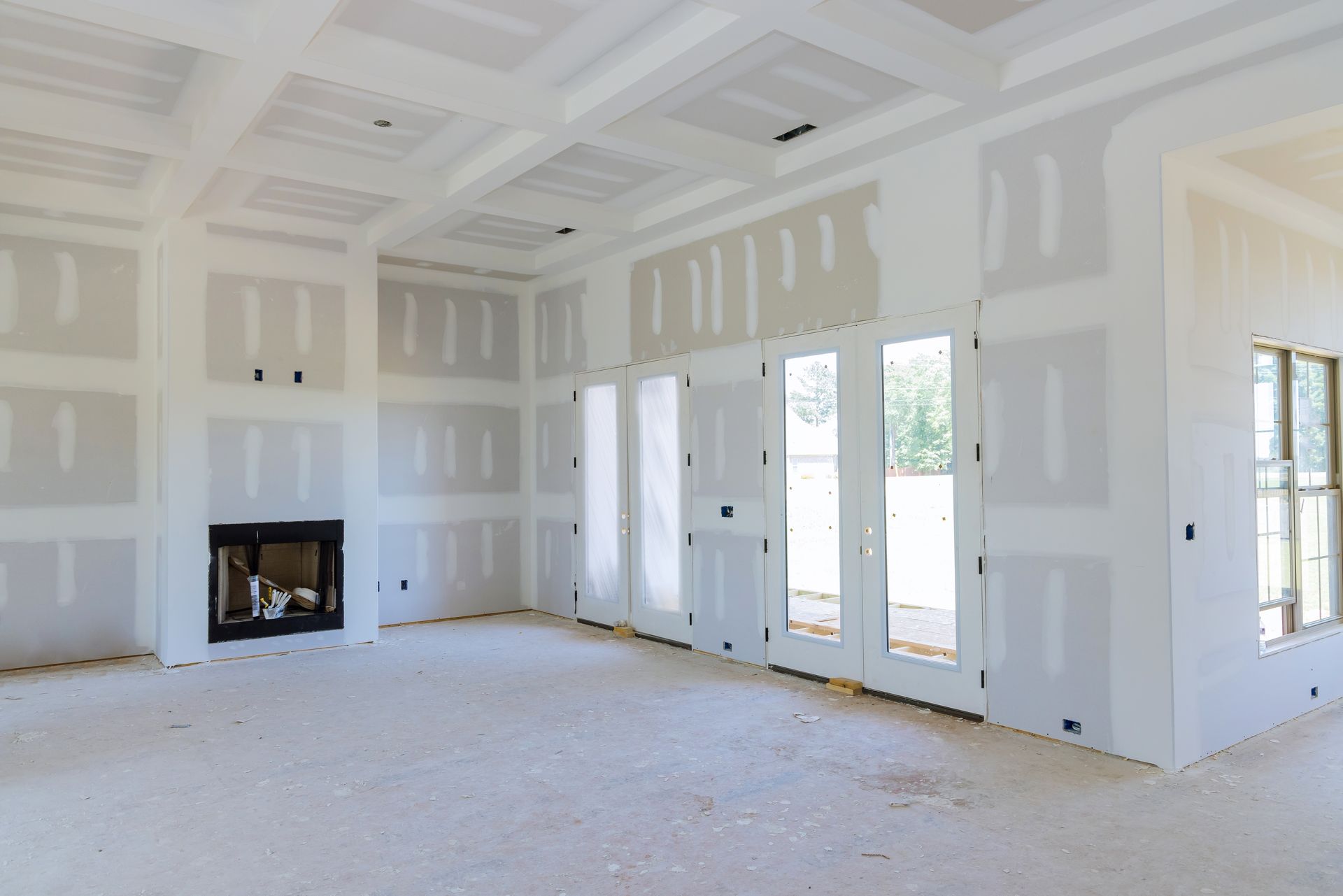 Interior room with drywall installation, fireplace, and french doors. White surfaces, unfinished construction.