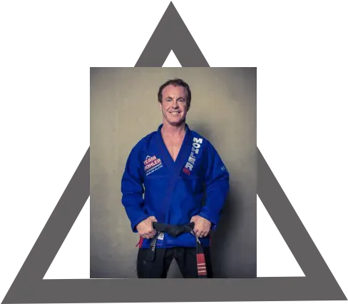 A man in a blue karate uniform is holding a black belt.