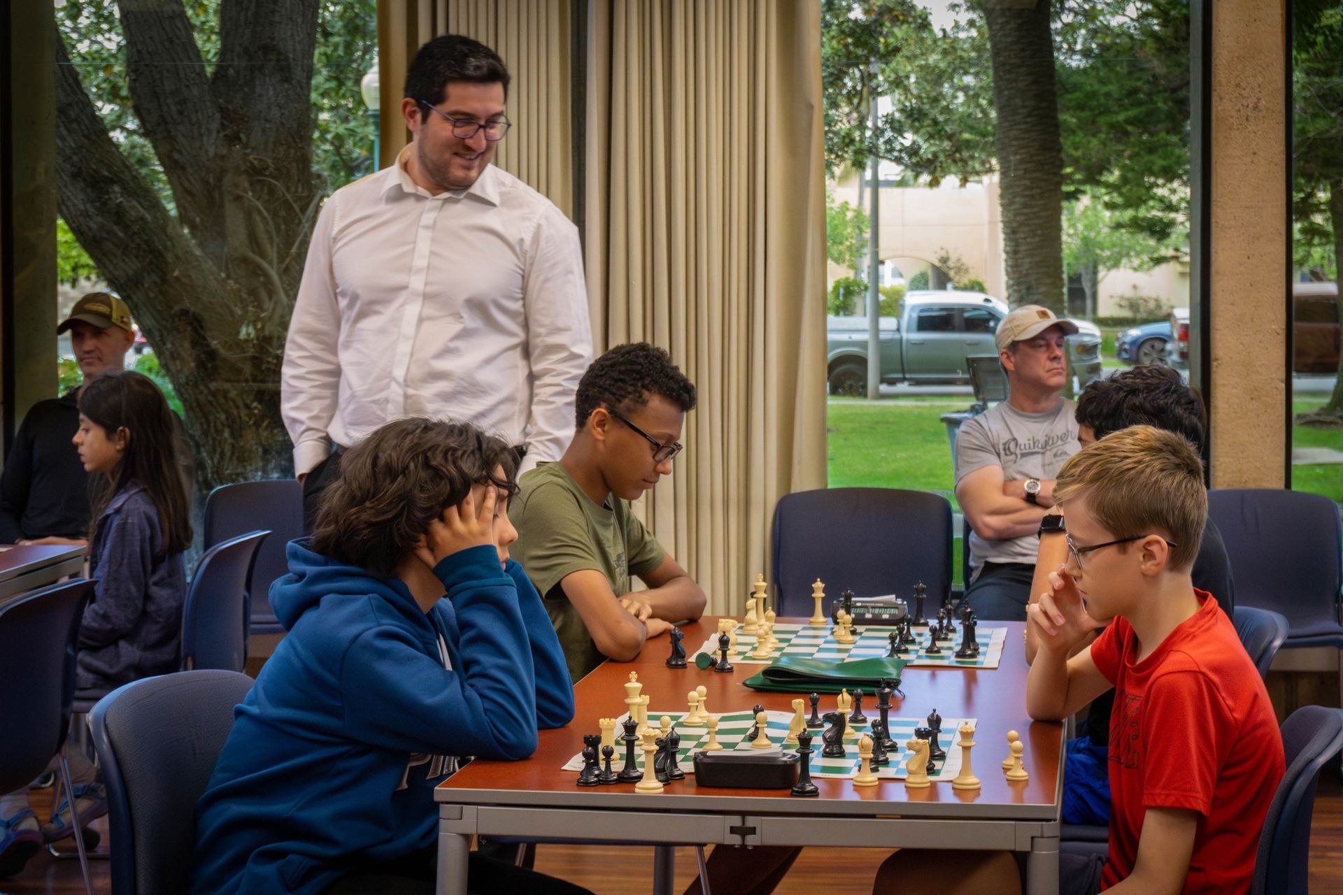 A group of people are playing chess in a room.