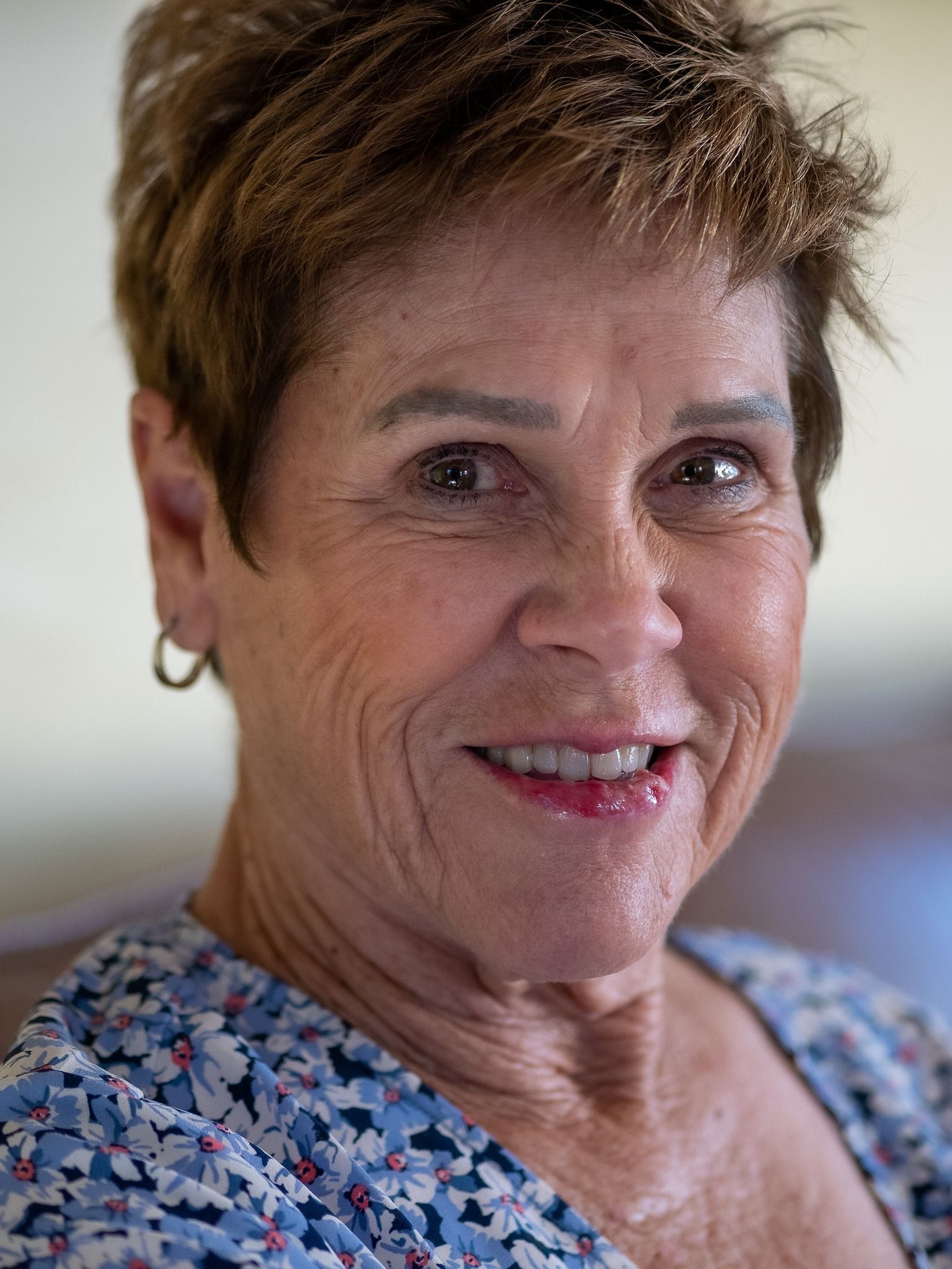 A close up of a woman 's face wearing a blue shirt and smiling.