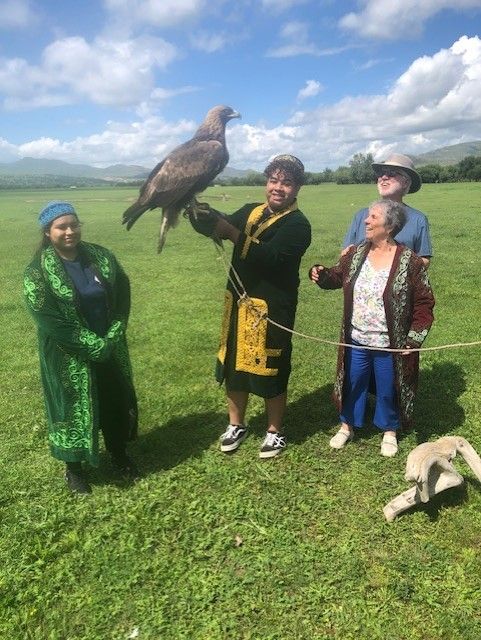 A group of people are standing in a field holding an eagle.