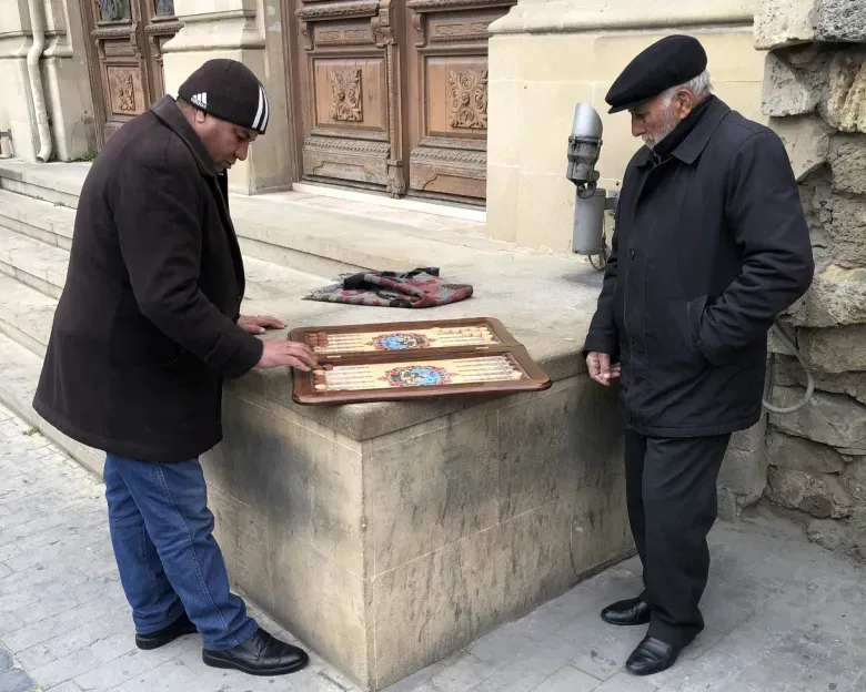 Two men are playing a game of chess on the sidewalk