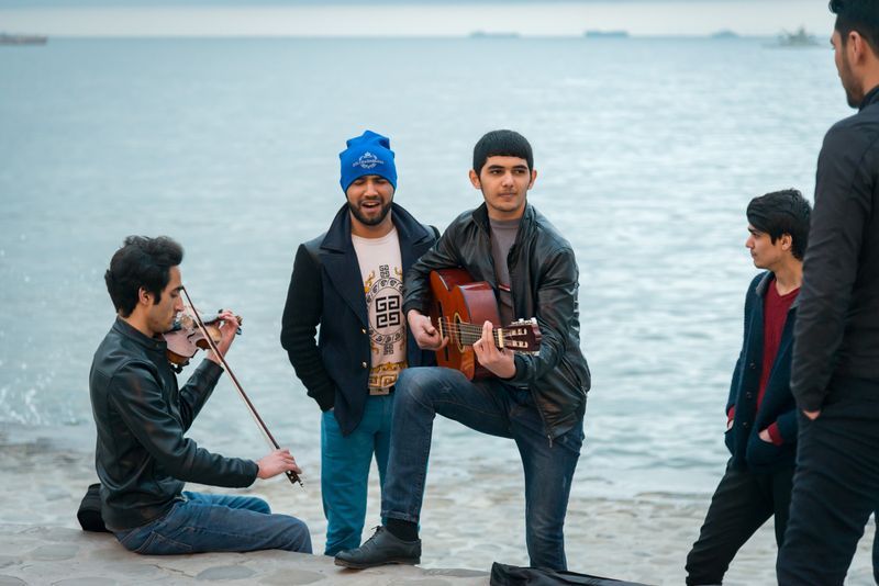 A group of young men are playing musical instruments on the beach.