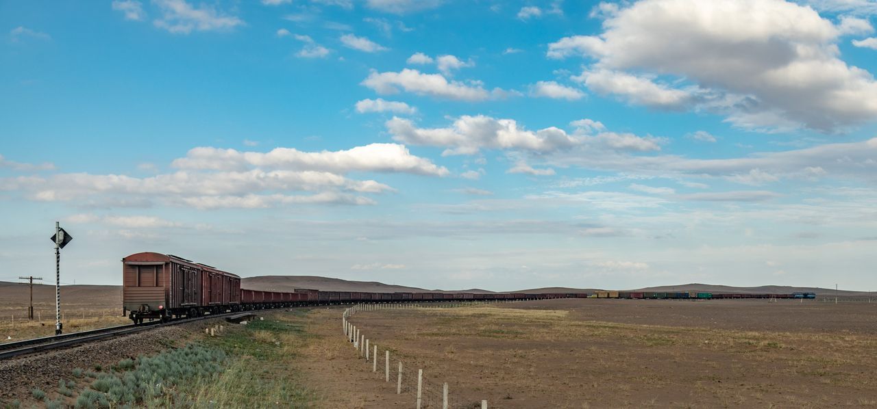 A train is going down the tracks in the middle of a field.