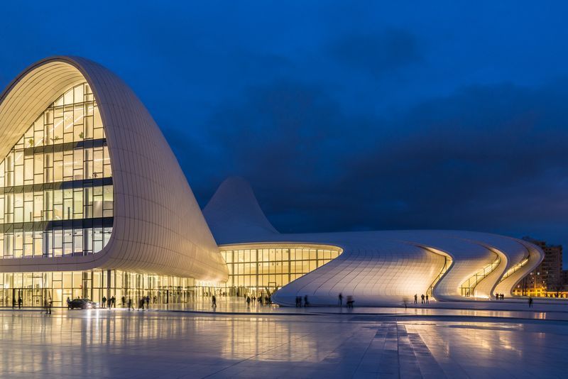 A large white building with a curved roof is lit up at night.