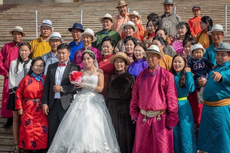 A bride and groom are posing for a picture with their family.