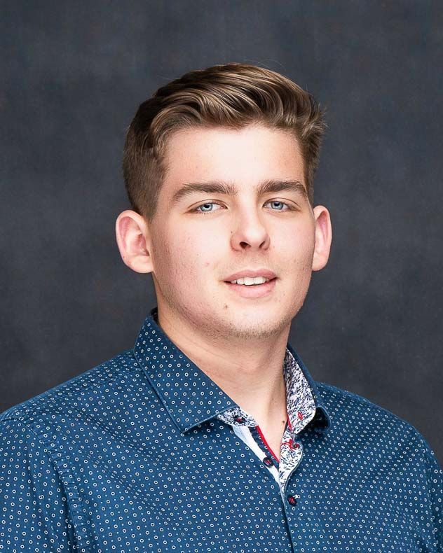 A woman is sitting at a desk with a laptop and a vase of flowers.