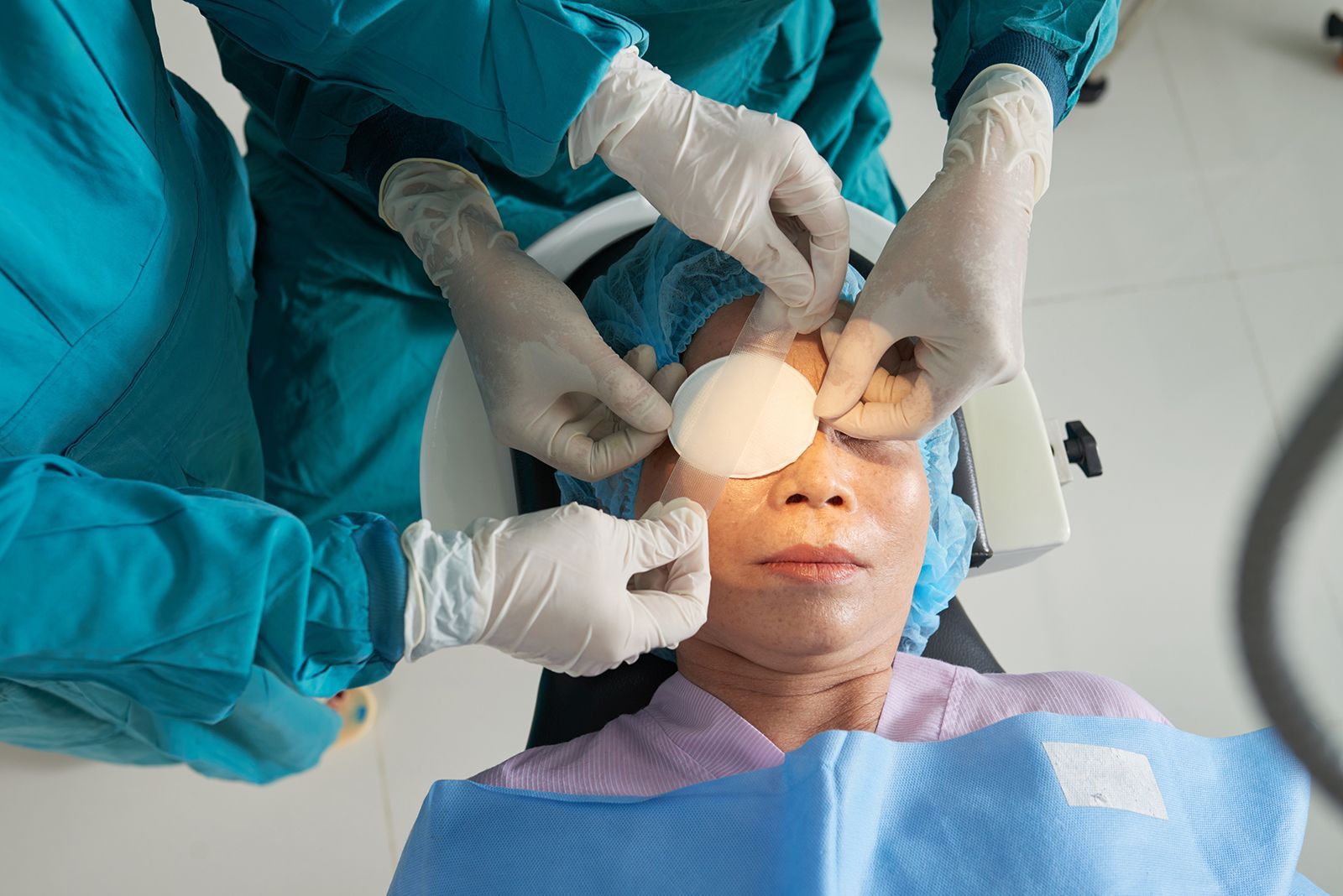 Paciente con el ojo tapado, siendo preparado para una cirugía por parte del personal médico.