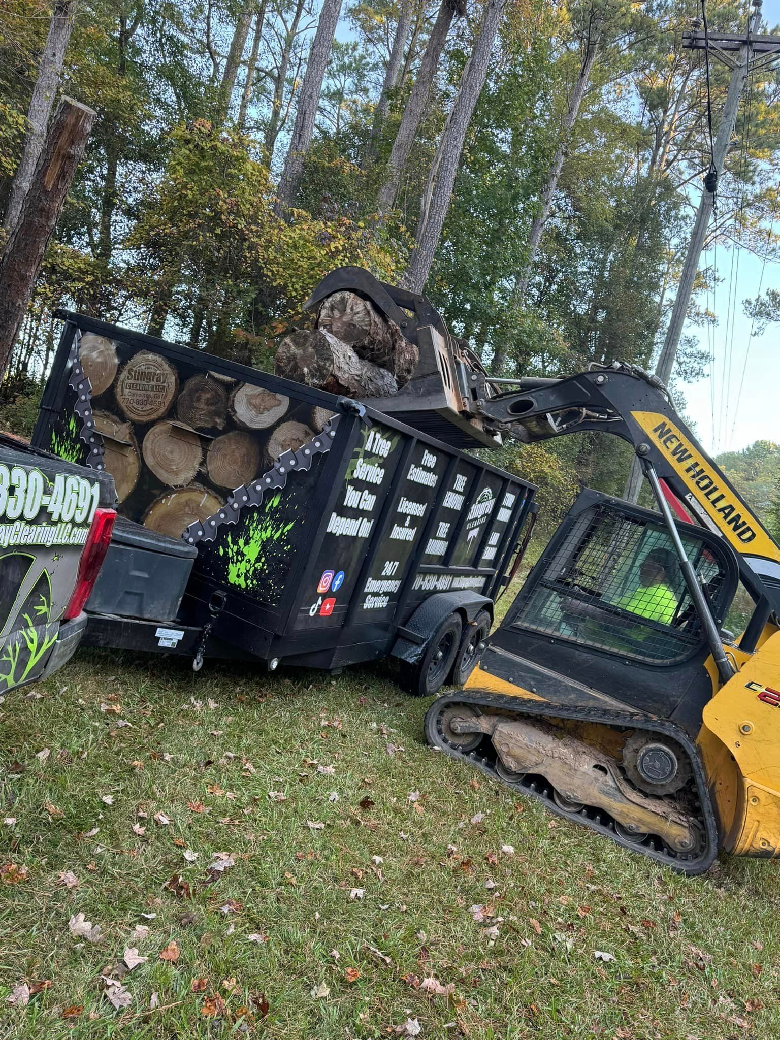 A bulldozer is loading logs into a dumpster.