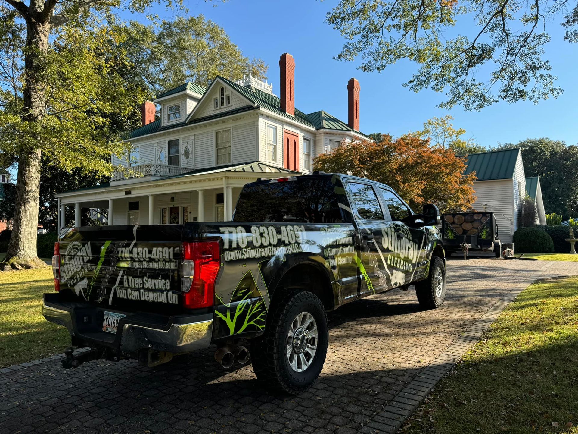 A truck is parked in front of a large white house.