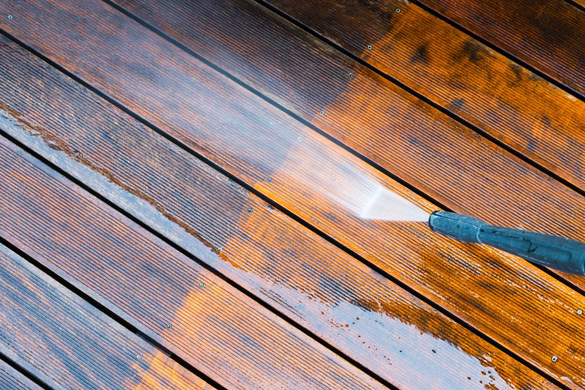 Pressure washing a wooden deck, showing the clean and dirty areas.