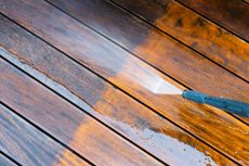 Pressure washing a wooden deck, showing the clean and dirty areas.