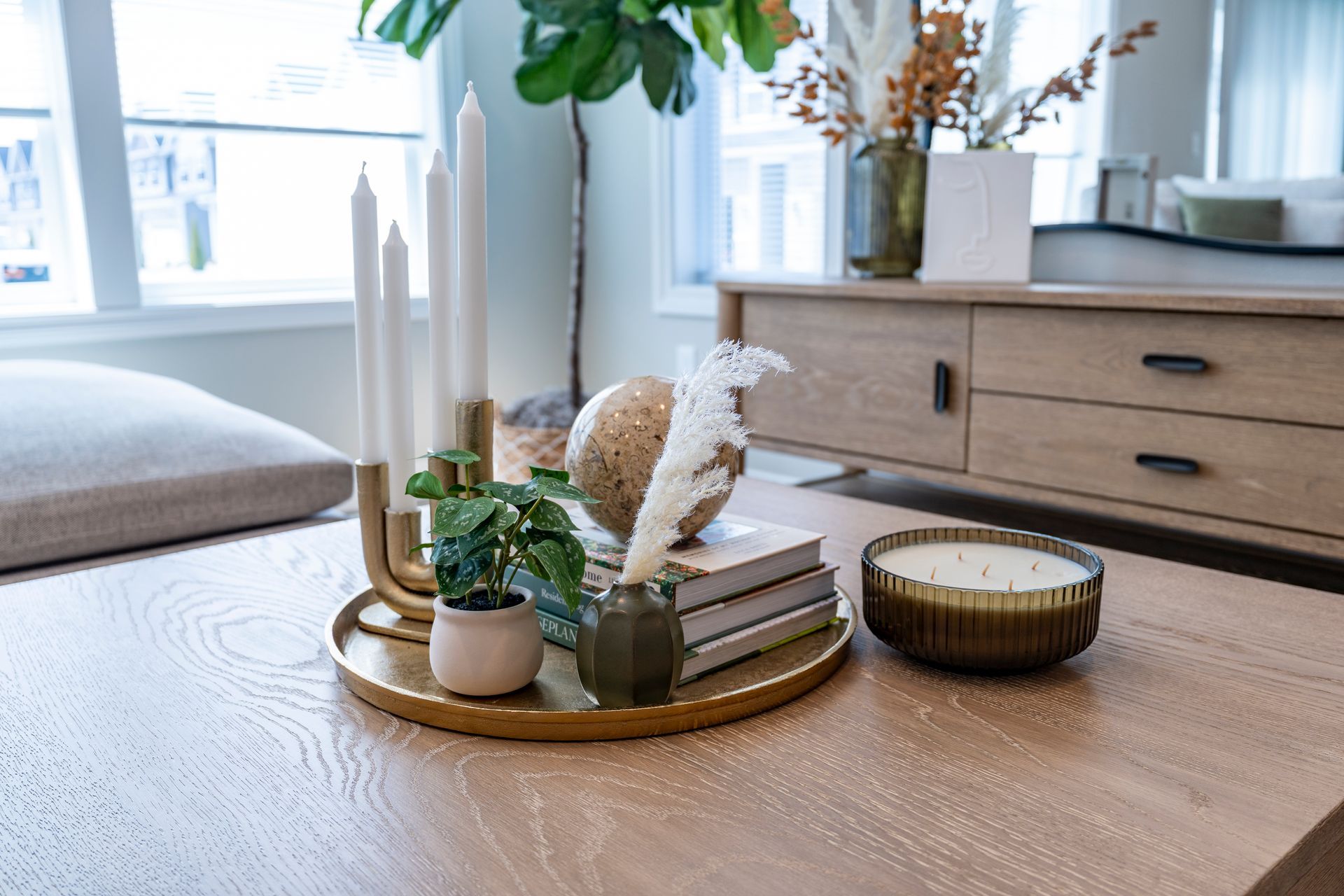 Table centerpiece with candles, plants, and books on a wooden table.
