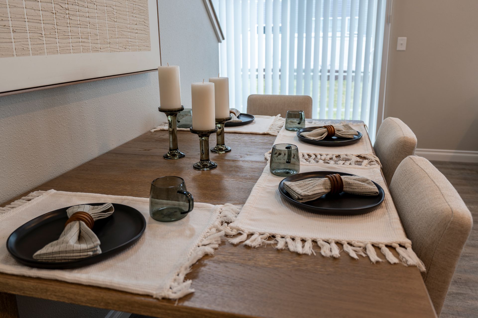 Dining table set for a meal, with candles and place settings. Sliding glass door is visible.