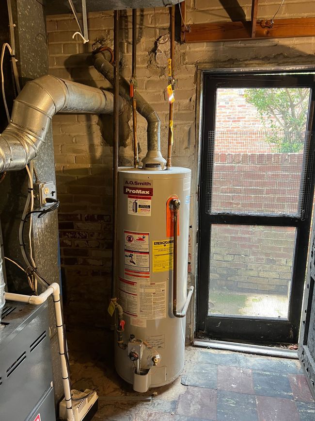 Basement utility room with water heater, exposed ductwork, and a window by concrete walls.