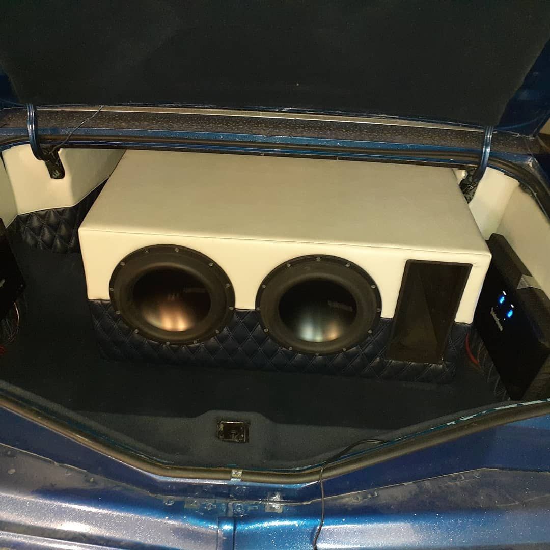 A car trunk customized with a white subwoofer enclosure and two speaker