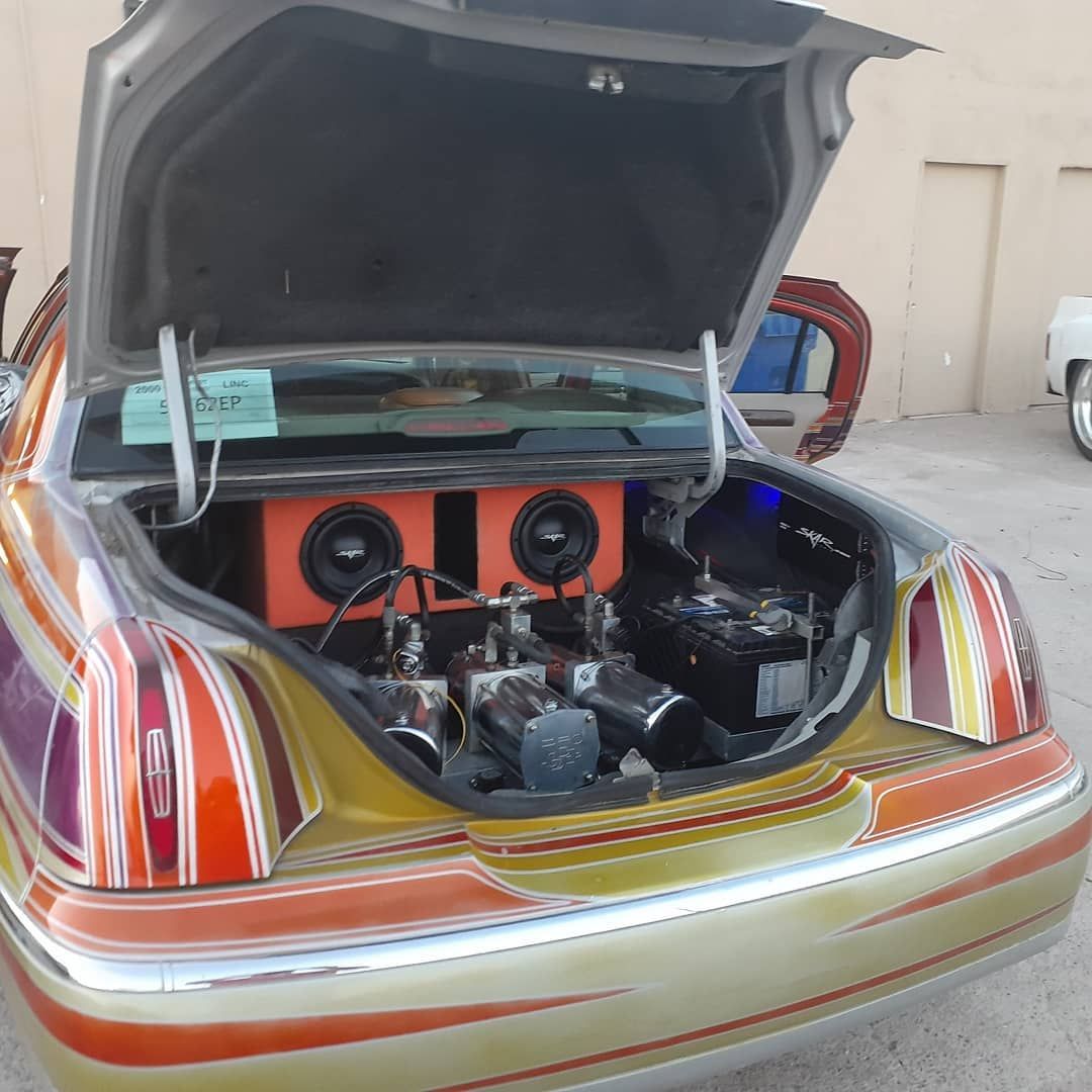 A lowrider car with its trunk open, revealing a customized sound system 