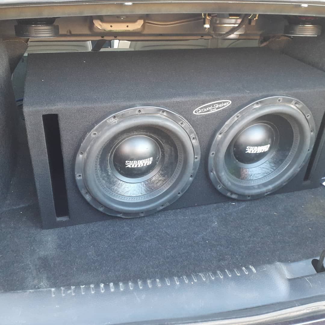 Black subwoofer enclosure with two speakers in a car trunk. Trs.