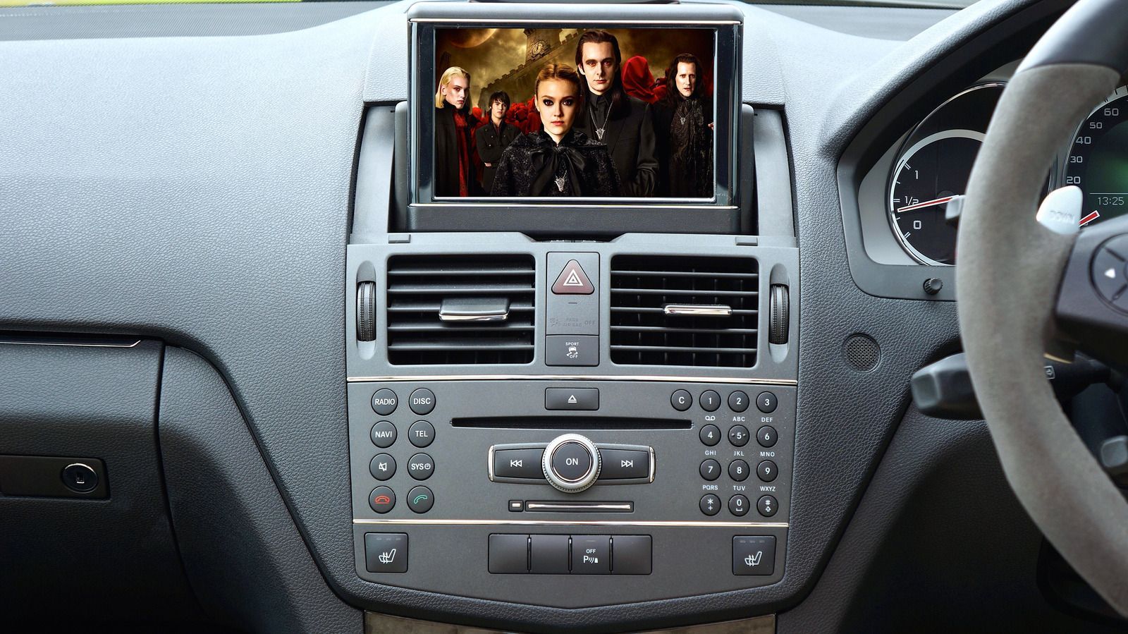 Car dashboard with a screen playing a movie; interior shot. The screen displays