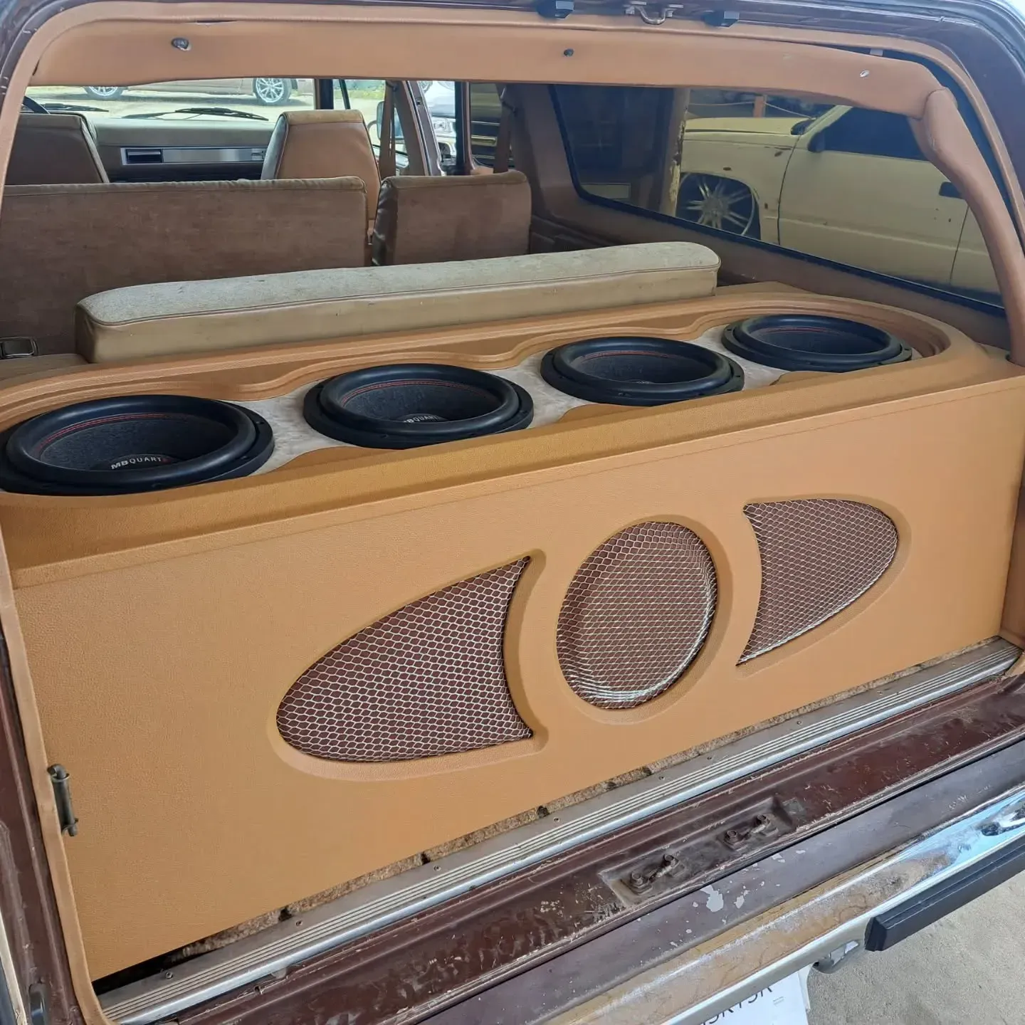 Inside a vehicle, a custom audio setup with four subwoofers and two mid-