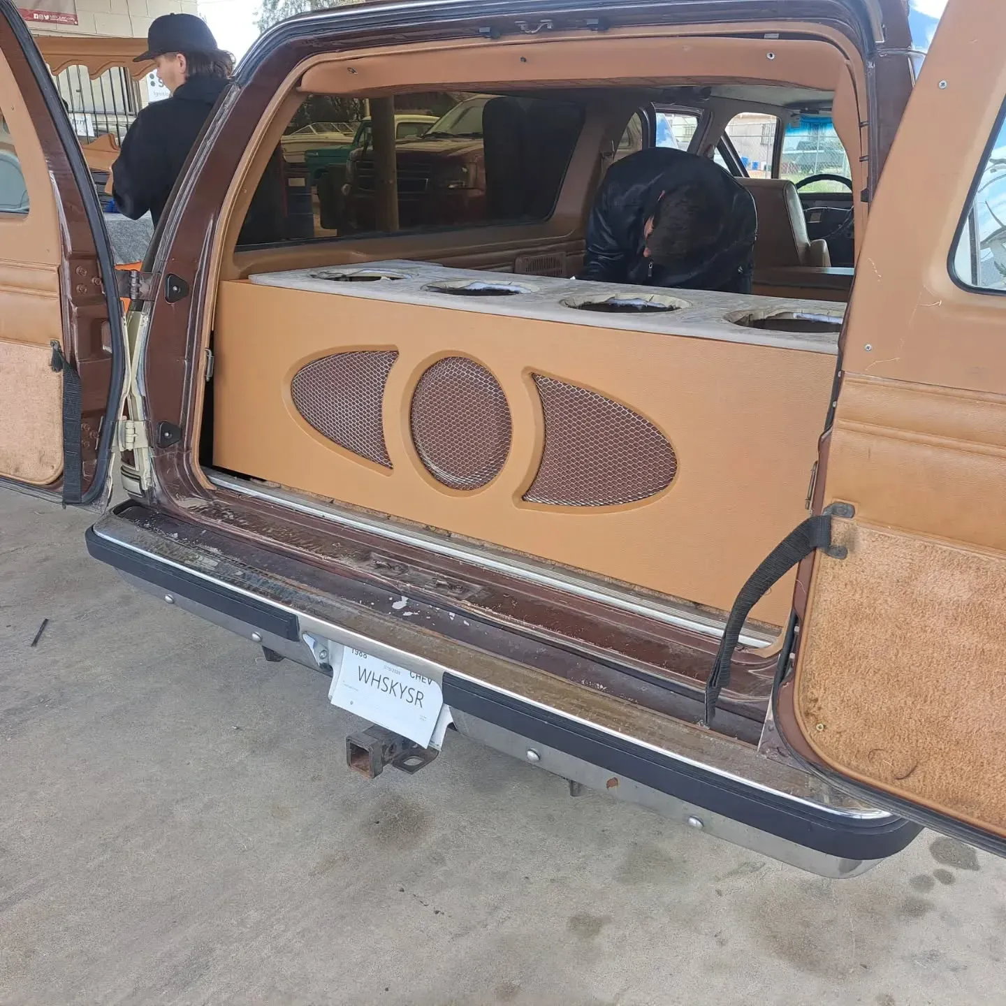 Open door of a brown classic SUV displaying a custom-built sound system with speakers, showcasing audio installation.