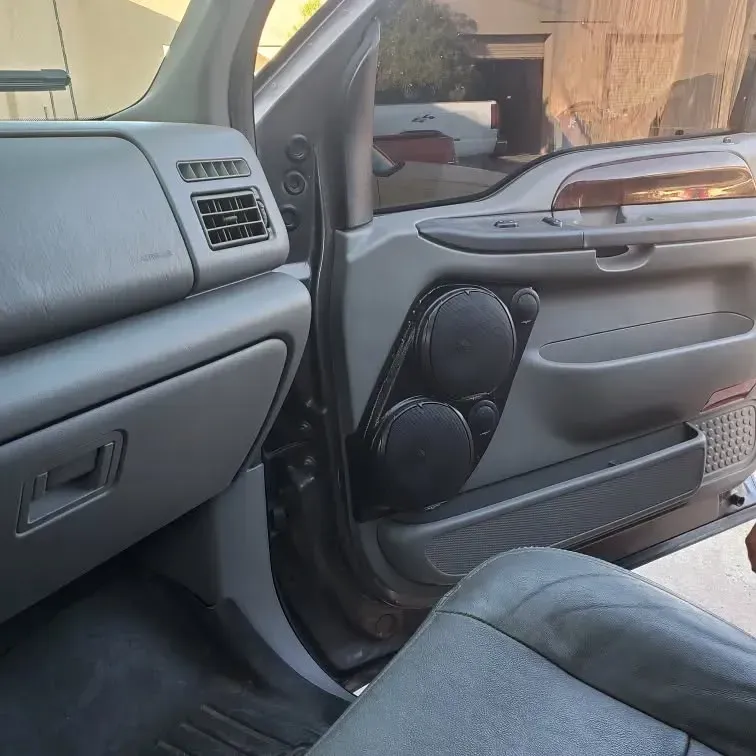 Interior of a gray truck cab. The door panel has aftermarket speakers. The dashboard and seat are visible.