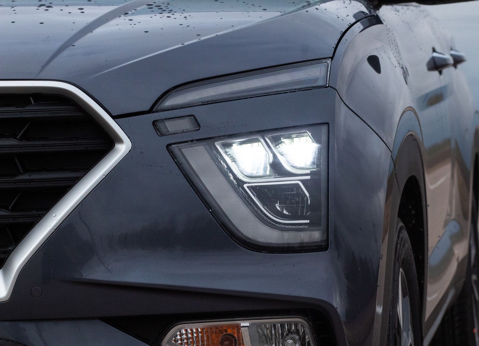 Close-up of a dark blue car's headlight, showcasing the LED lights and design details.