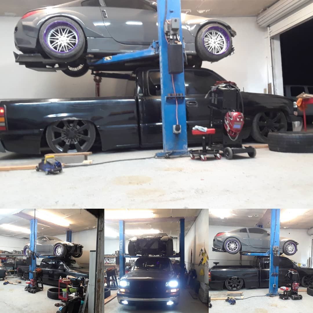 Black cars in a garage; a truck and sports car are on a lift.  A lower-level view shows other work stations.