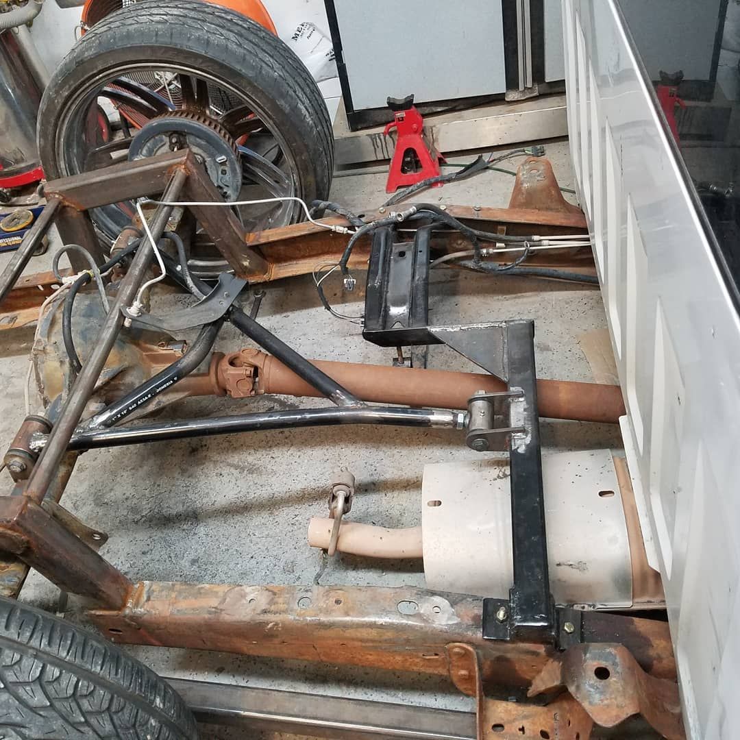 Undercarriage of a pickup truck with exposed frame and rear suspension, showing exhaust and other mechanical components.
